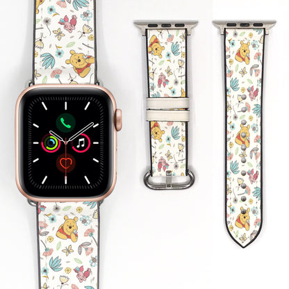 Close-up of a cream character-print Apple Watch band with colorful flowers, leaves, and silver-tone hardware.