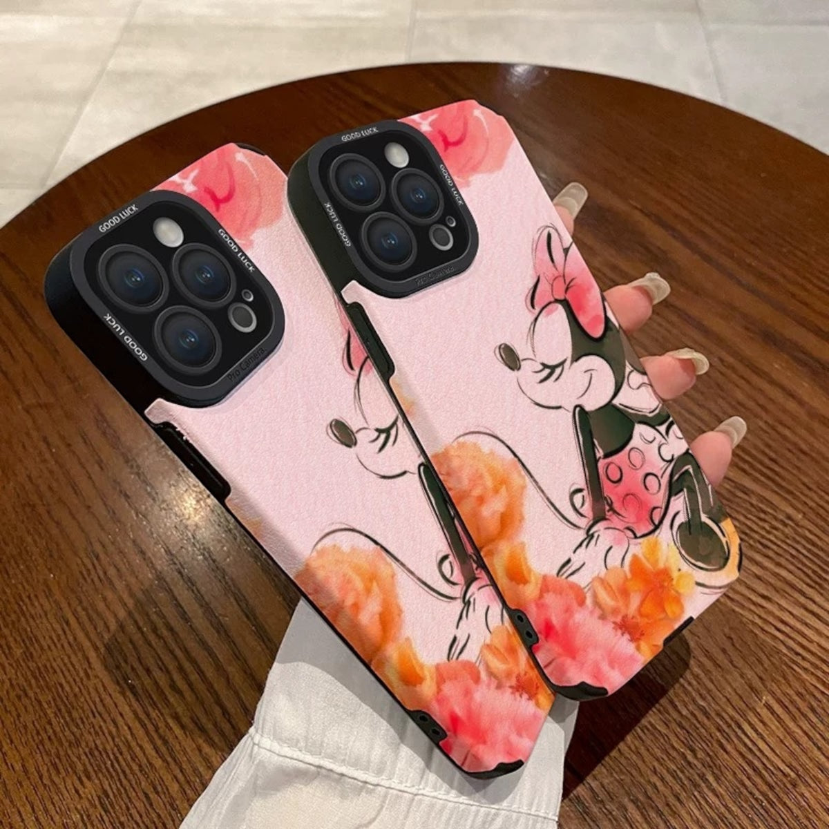 Pink iPhone case with cartoon character Disney Minnie Mouse design held by a hand