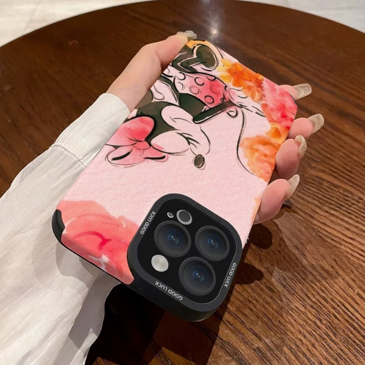 Pink iPhone case with cartoon character Disney Minnie Mouse design held by a hand