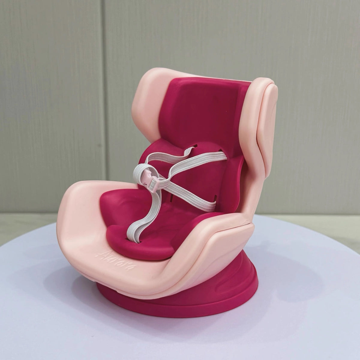 Pink and red baby seat with straps on a white surface