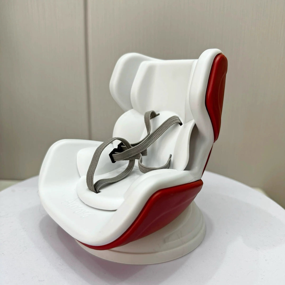 White and red baby car seat with gray straps on a white surface.