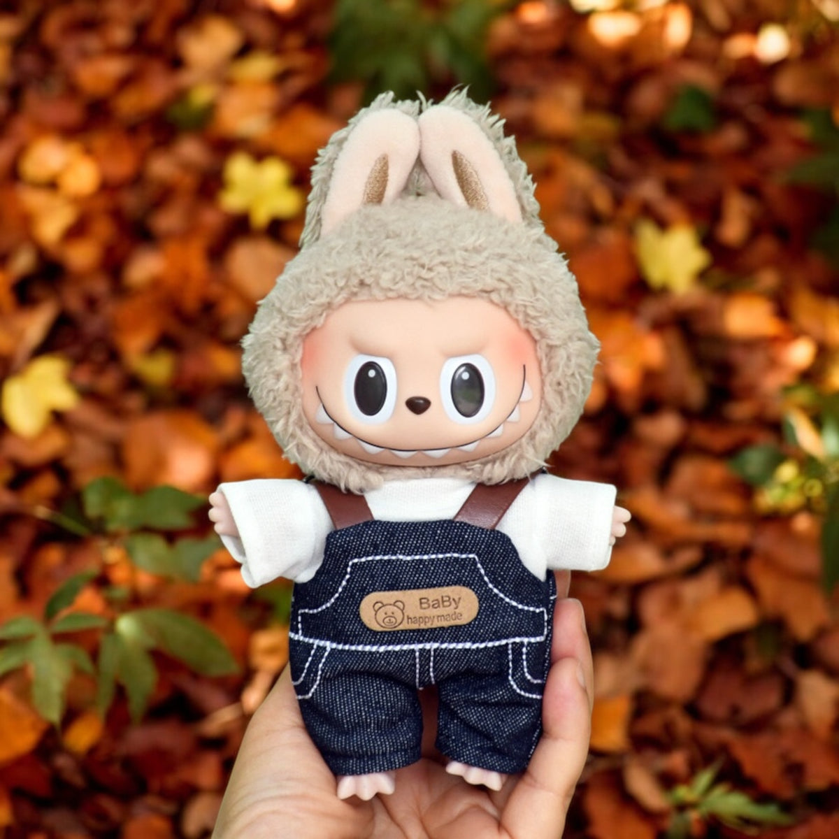 A Labubu Doll wearing a fall in Winter outfits holding by a hand in the forrest