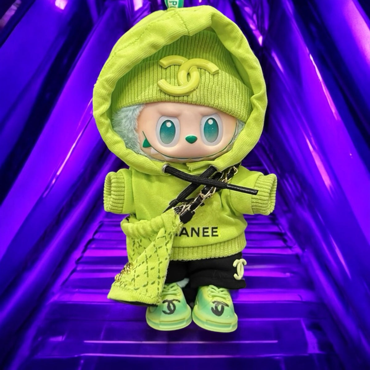 Toy figure in a bright green outfit with a Chanel logo on a purple background