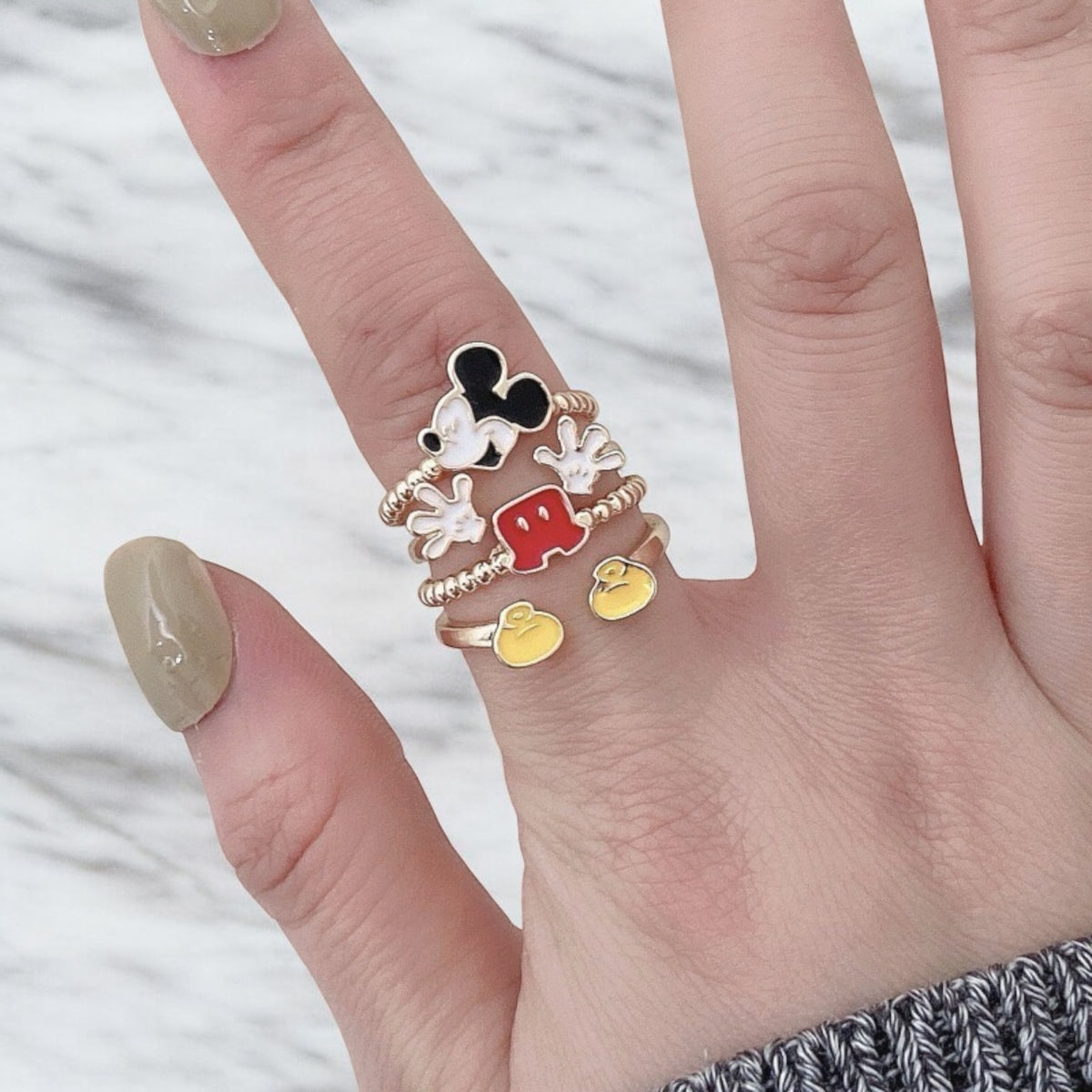 Hand wearing a cartoon-themed Vintage Mickey Mouse ring with a white background