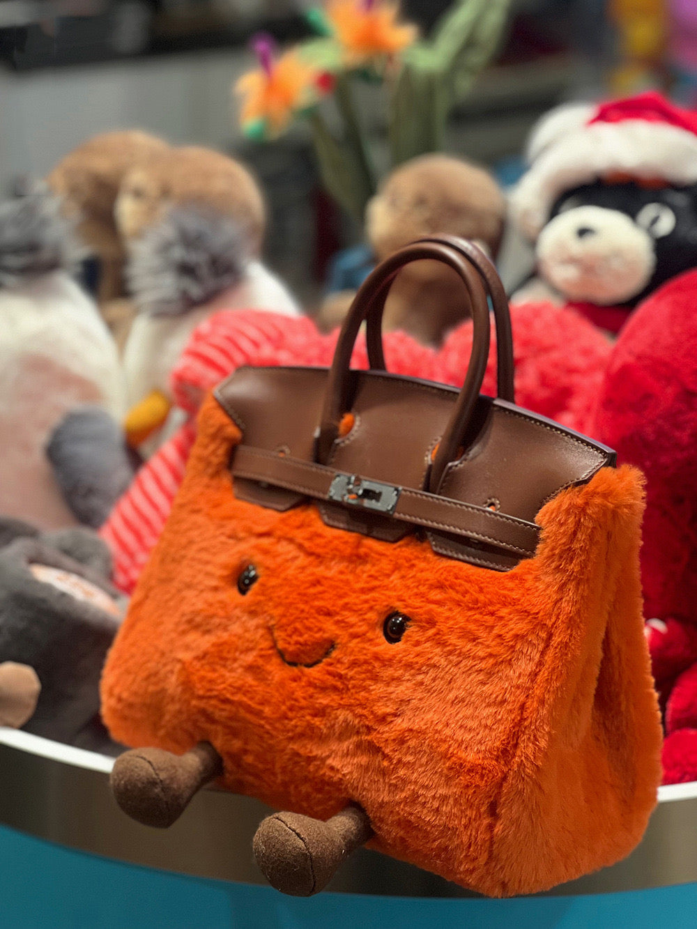 Close-up of orange plush bag with embroidered smiley face and silver-tone clasp