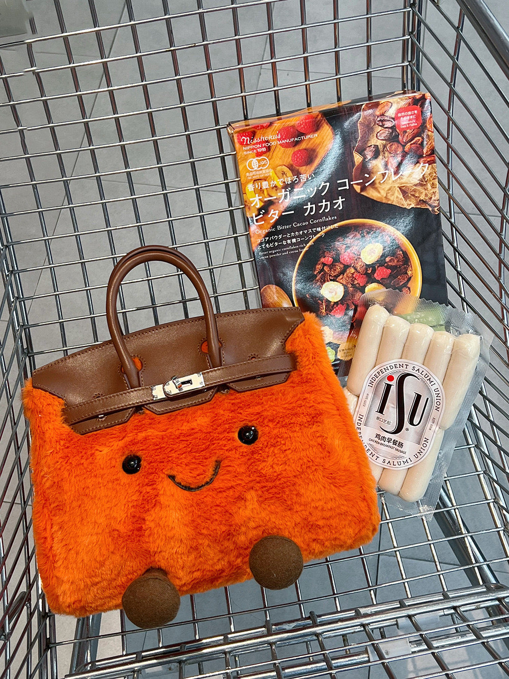 Mini orange plush bag with a smiley face and brown handles with supermarket cart background