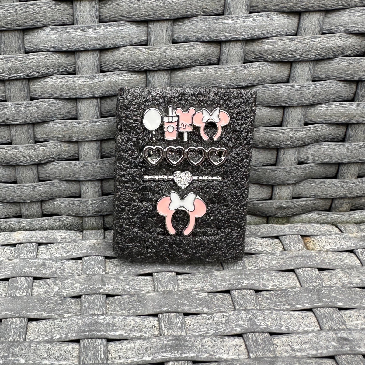 Black glittery case with decorative minnie mouse theme park snack charms on a woven surface