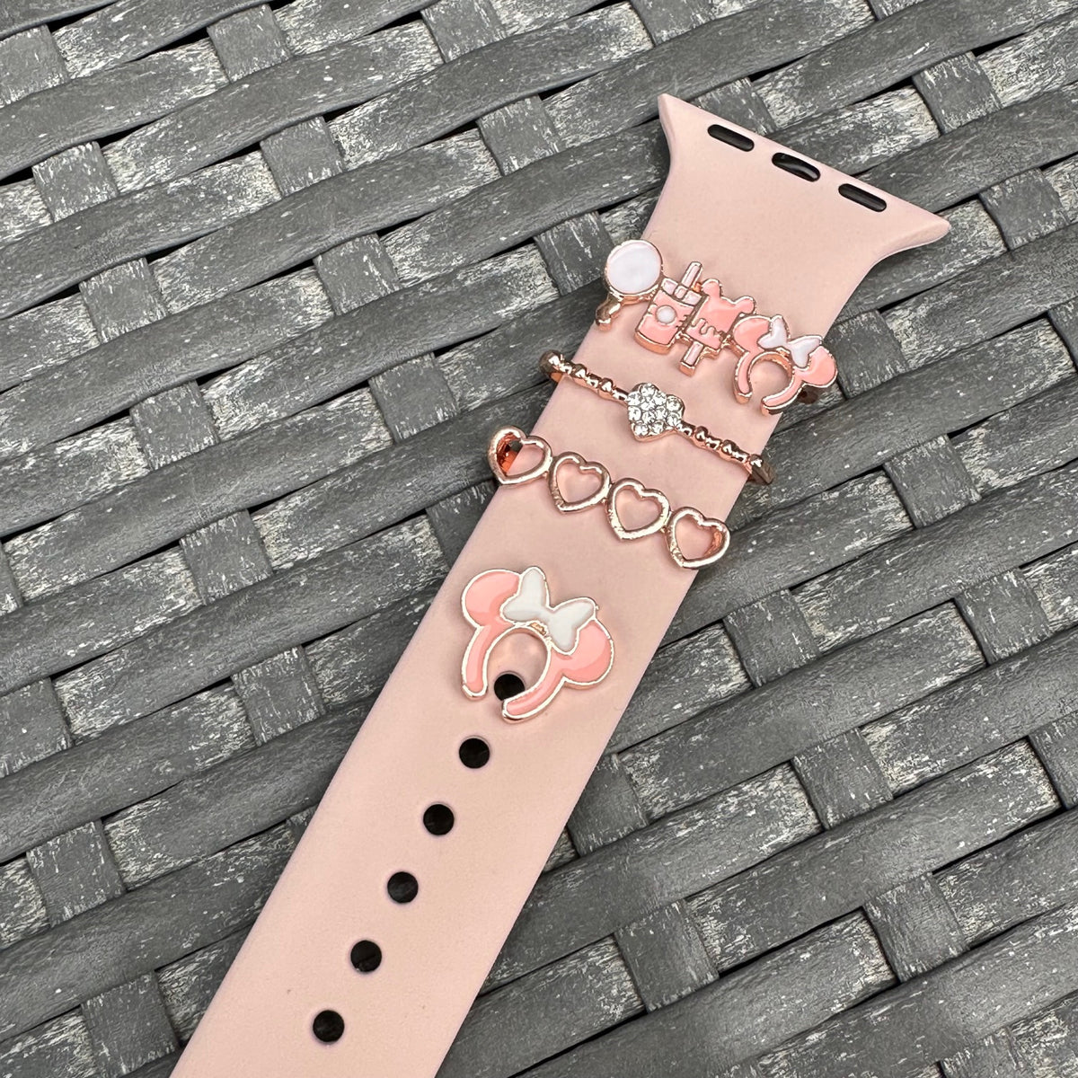 Decorative watch band with minnie mouse theme park snack charms on a textured surface